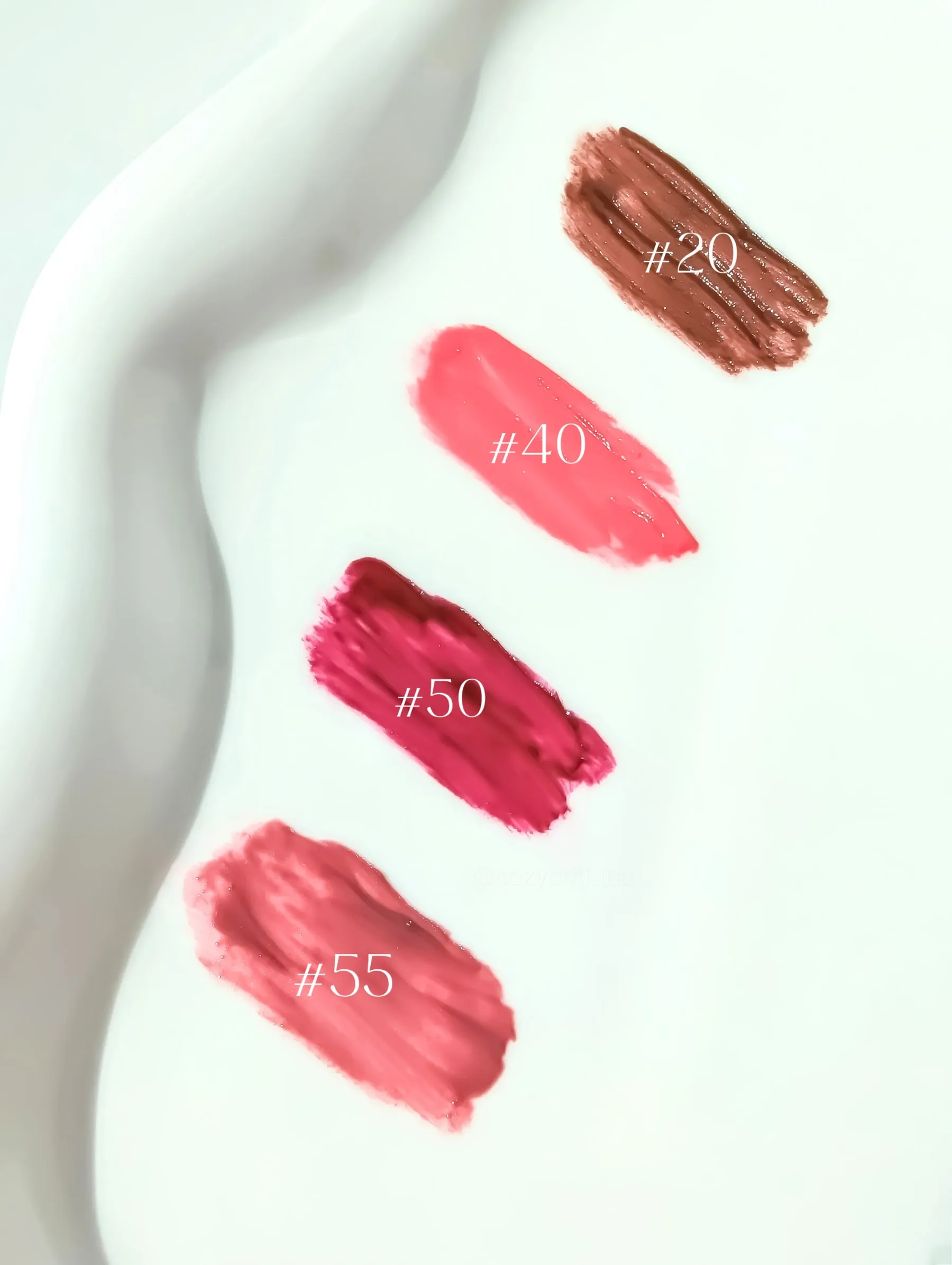 Four lipstick swatches on white background, labeled #20 (brown), #40 (pink), #50 (red), #55 (peach). Wavy edge detail.