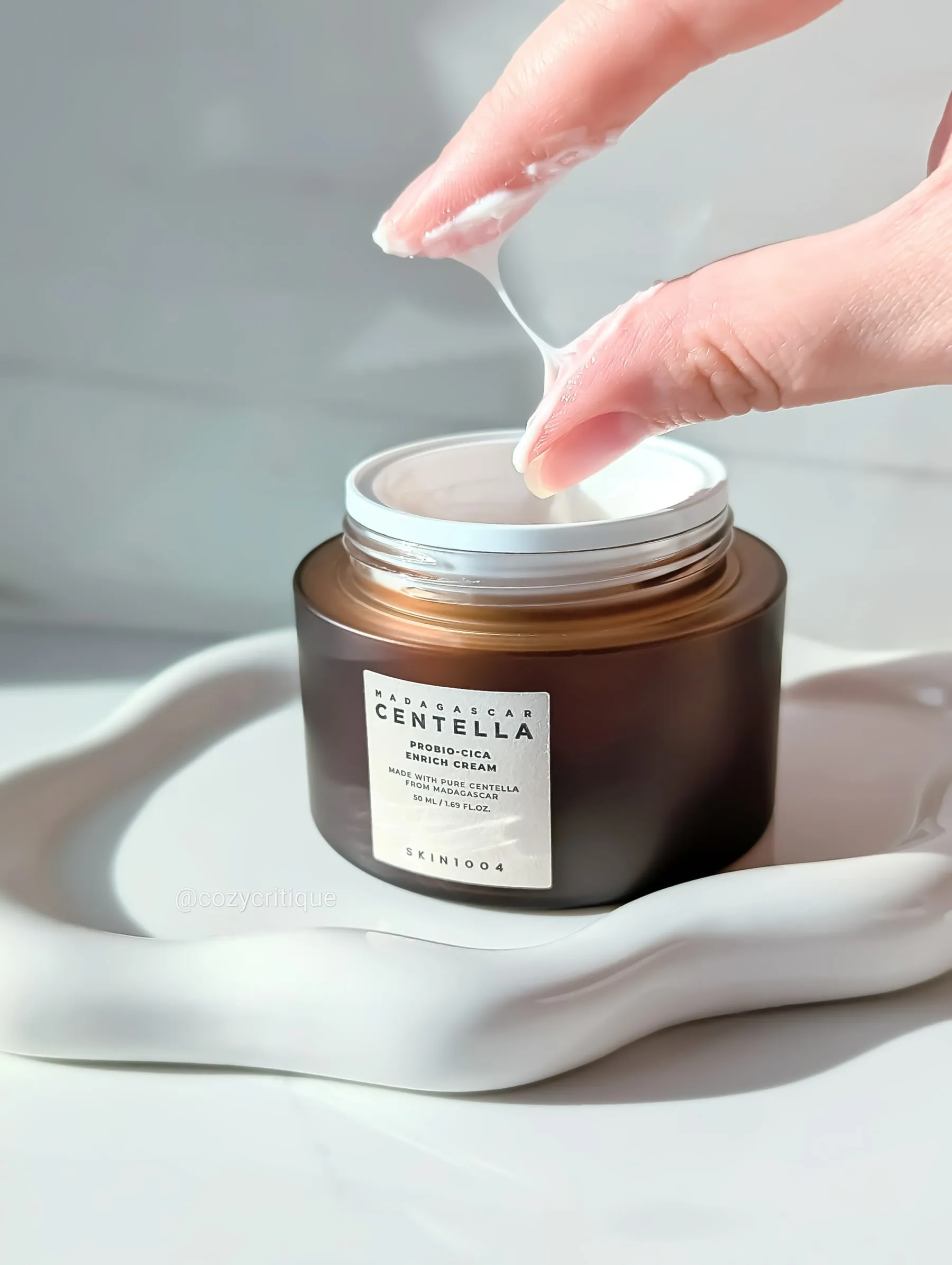 The SKIN1004 Probio-Cica Enrich Cream texture stretched between fingers