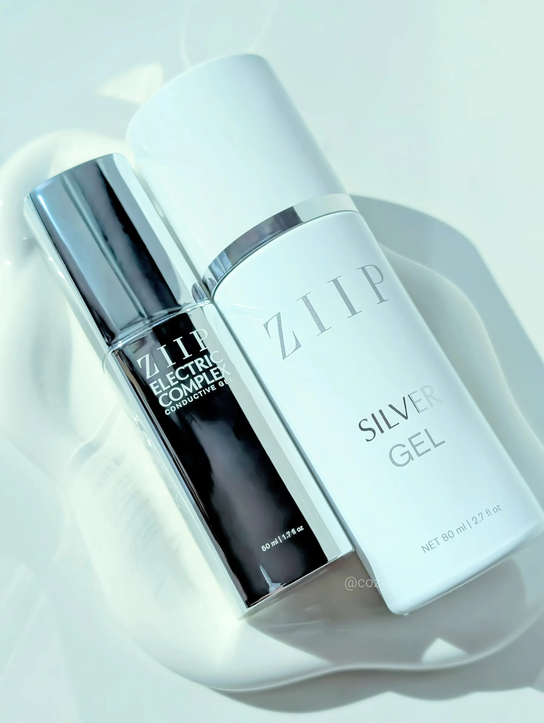 Two bottles, one metallic and the other white with "ZIIP Electric Complex" and "Silver Gel" text, on a glossy white surface.