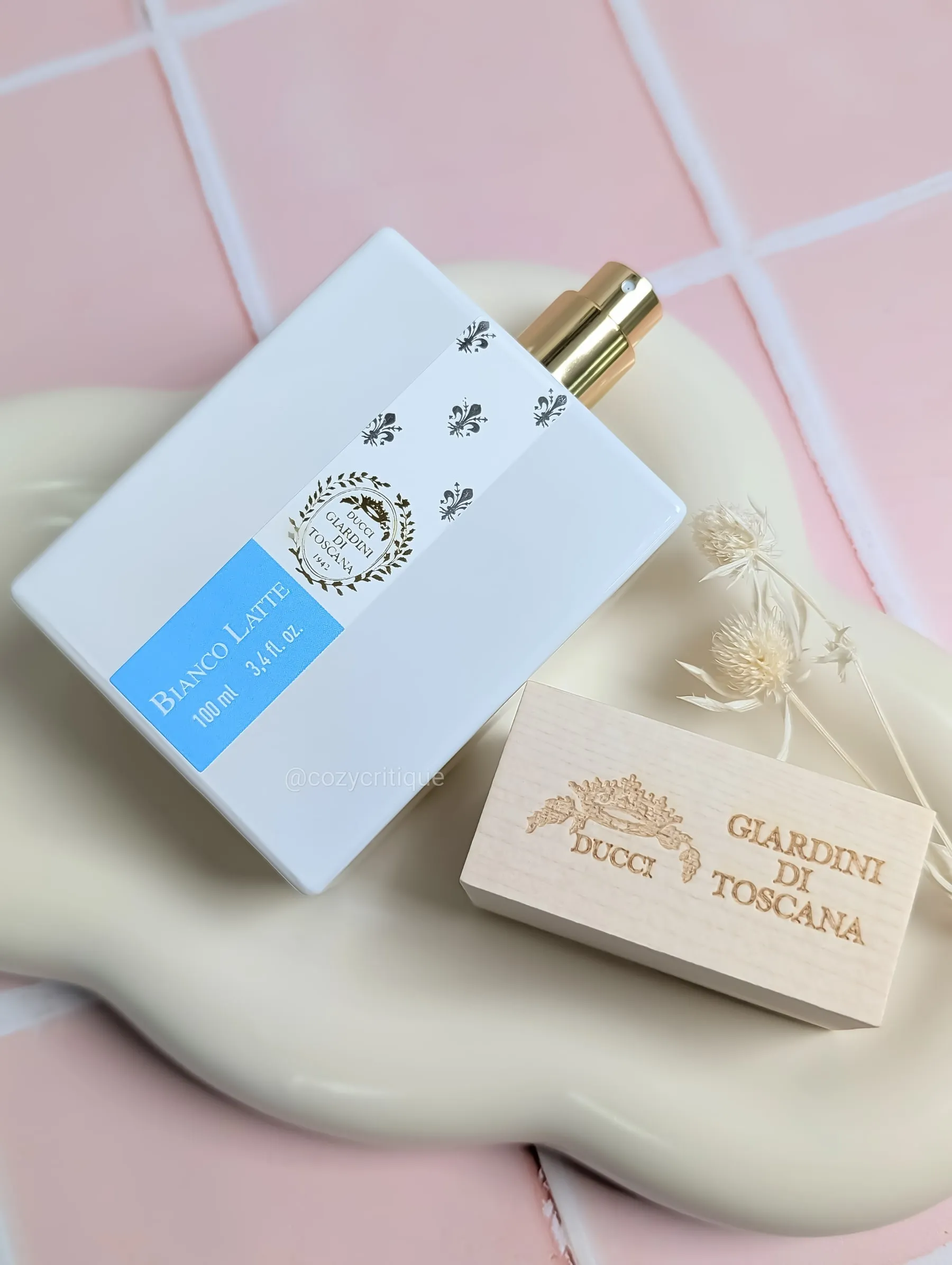 A bottle of Bianco Latte perfume with the lid off laying on a tray