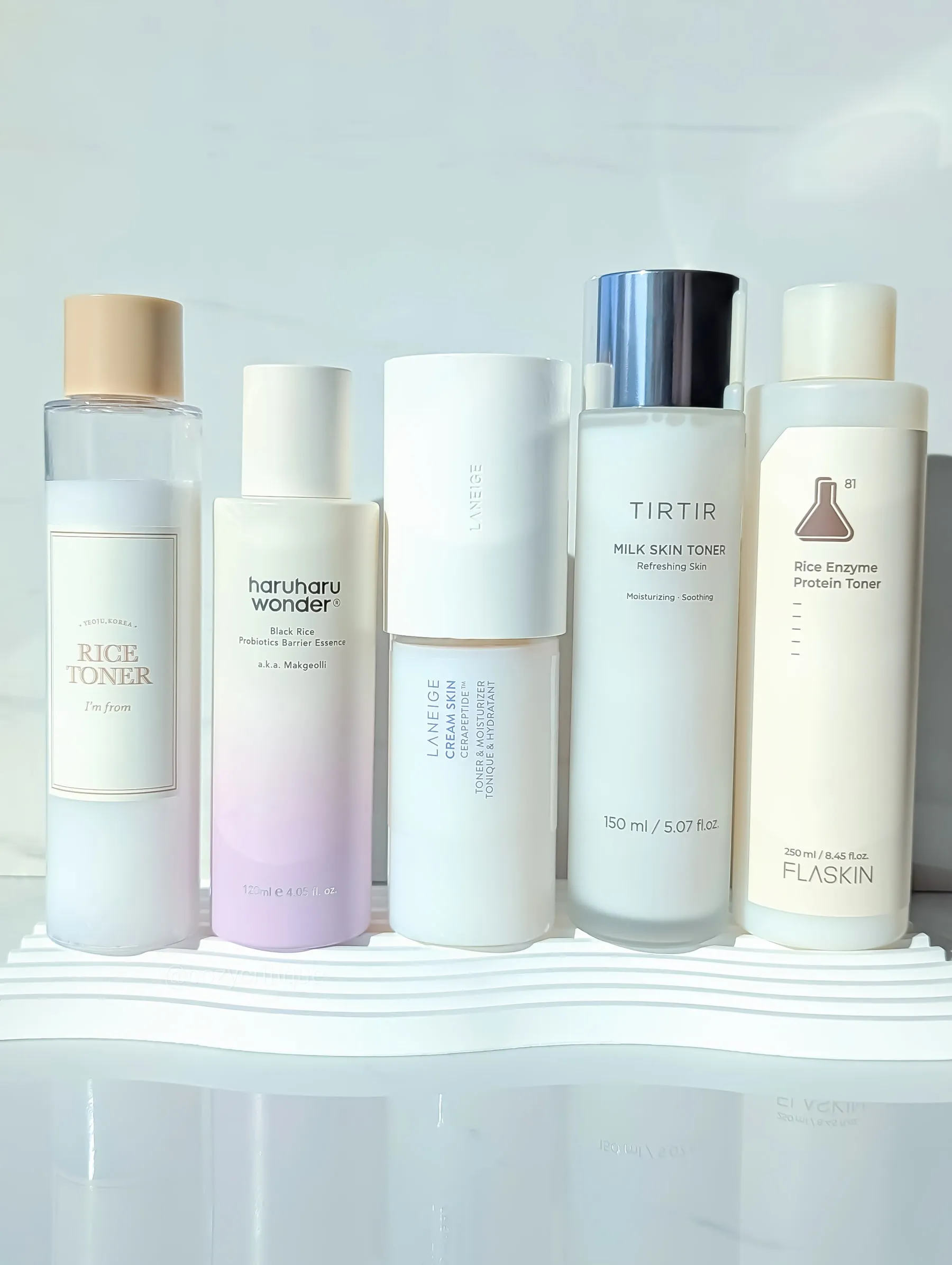 Five milky Korean toner bottles arranged together